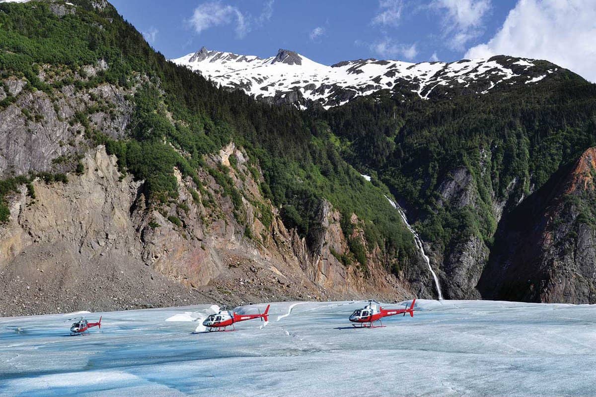 small red helicopters parked on top of a glacier