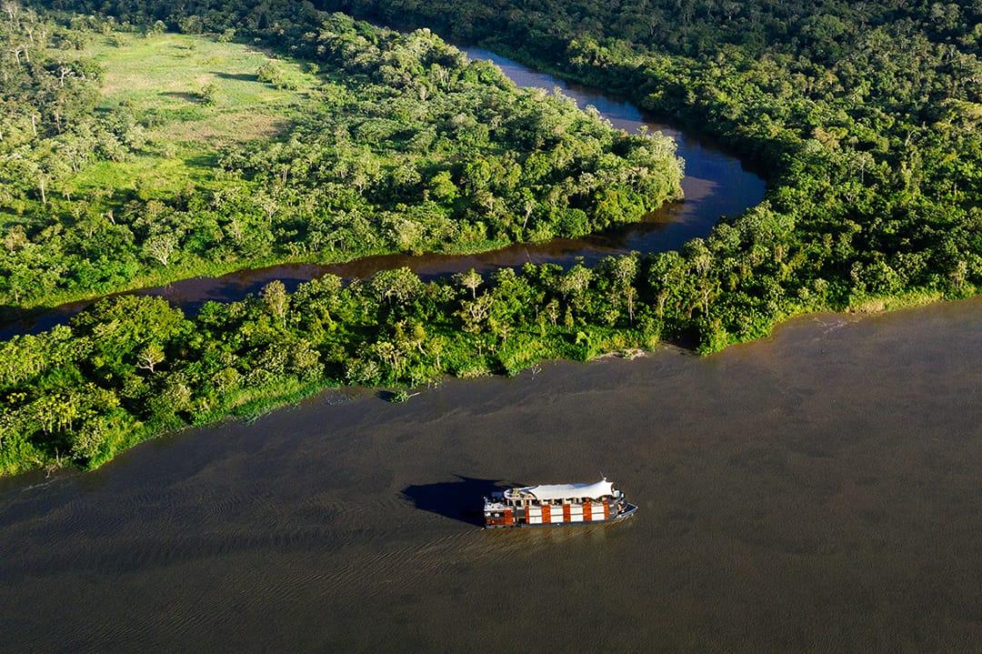 aerial view of the cruise boat on river with forest to one side