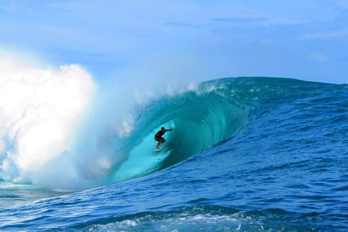 Surfer underneath a big blue wave