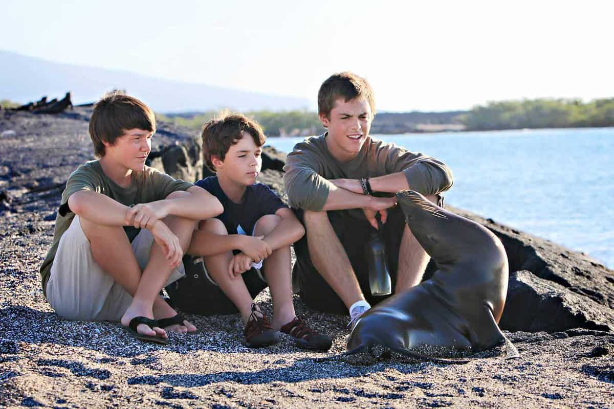 Three young boys sitting next to a small seal
