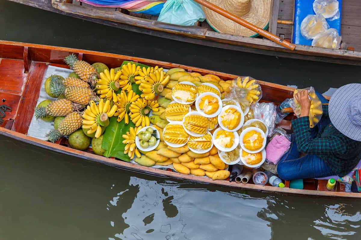 serial view of a small boat filled with fruits alongside other boats