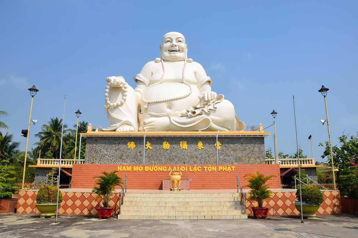 giant fat white buddha sitting on a stone plinth
