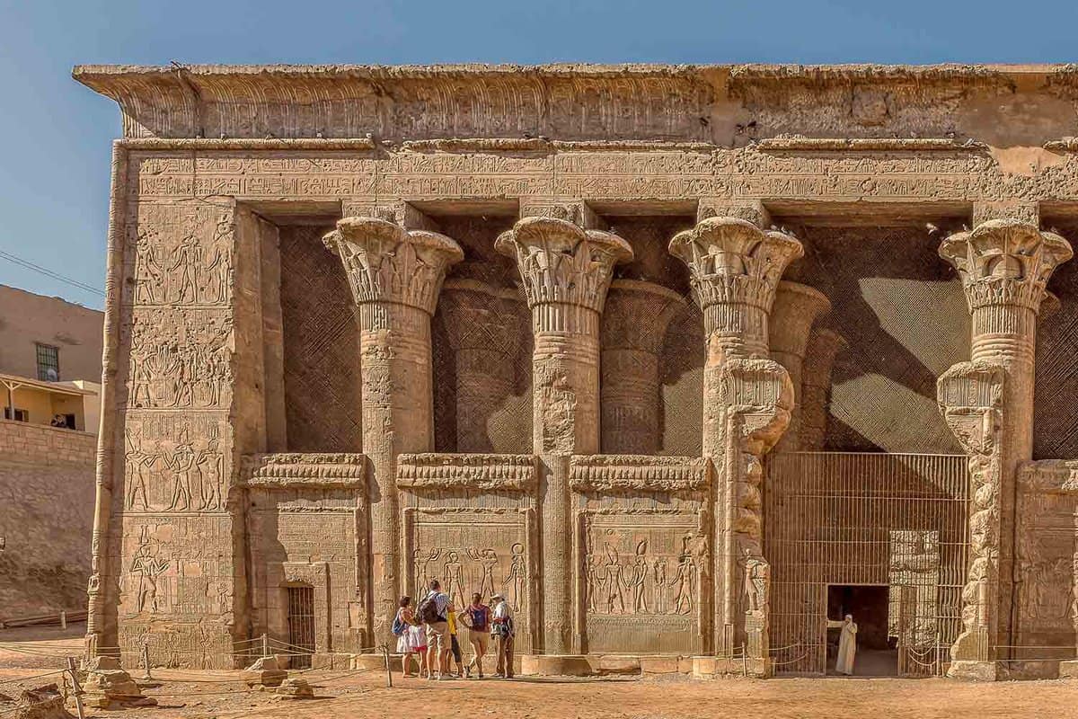 small group of tourists standing before the outside of the enormous temple