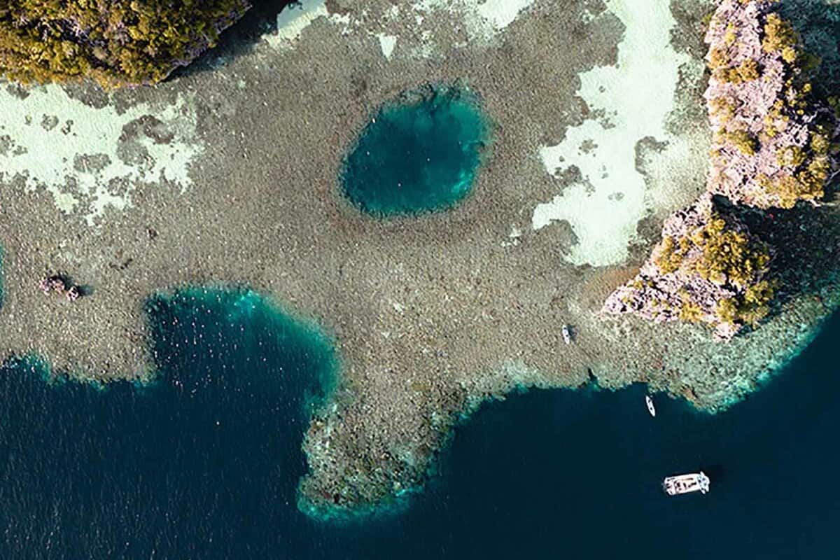 aerial view of small cruise boat moored next to a reef island