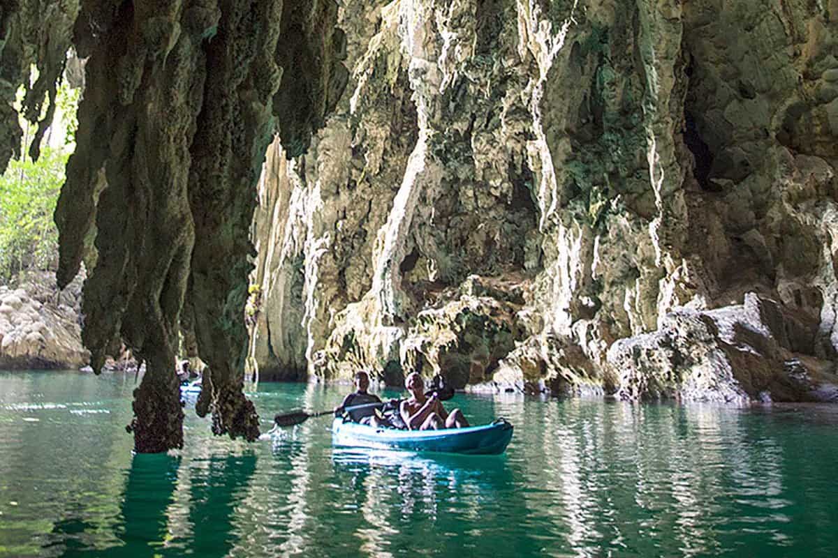two men kayaking into a spectacular cave with stalactites