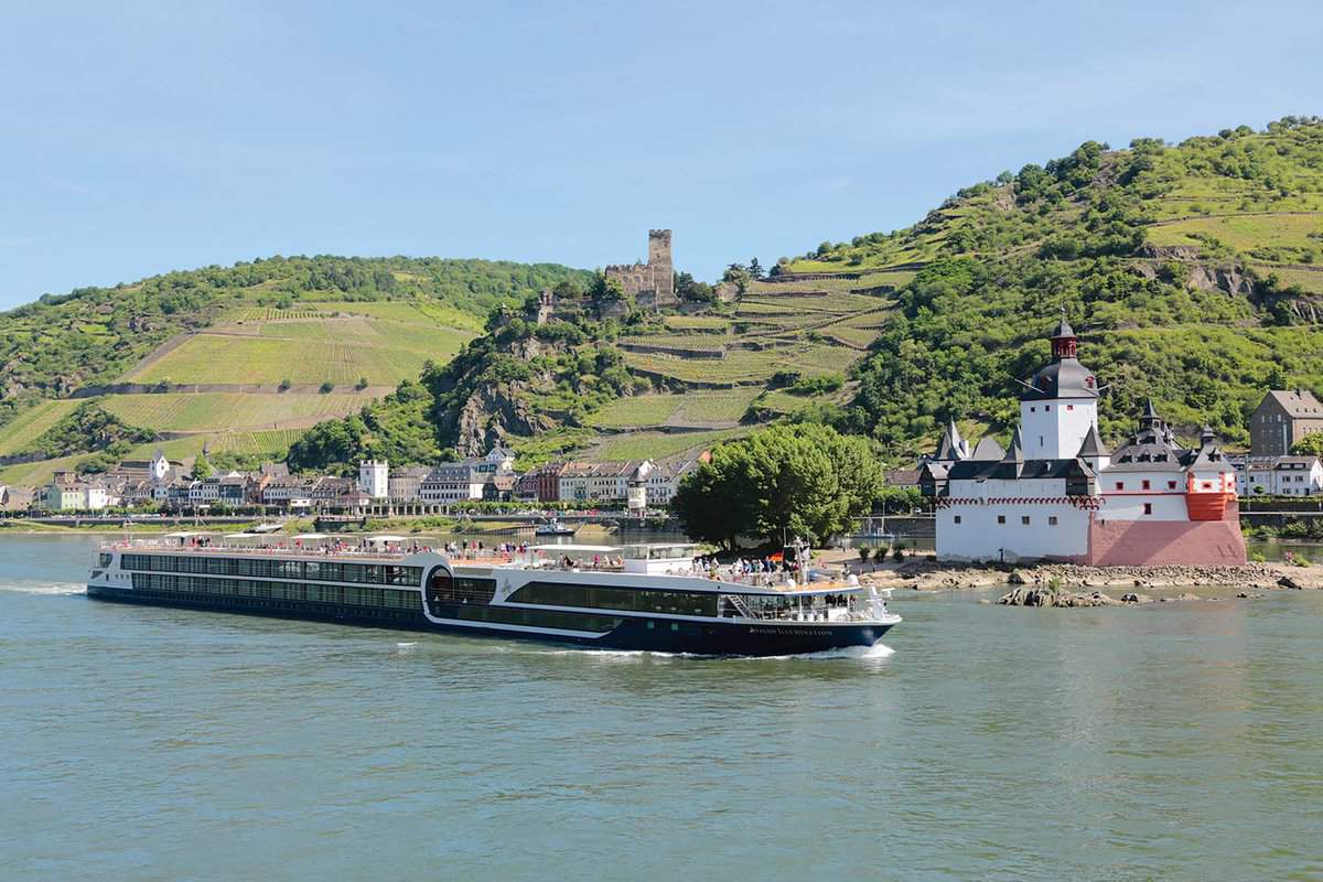 river cruising boat passing a small town on the river rhine
