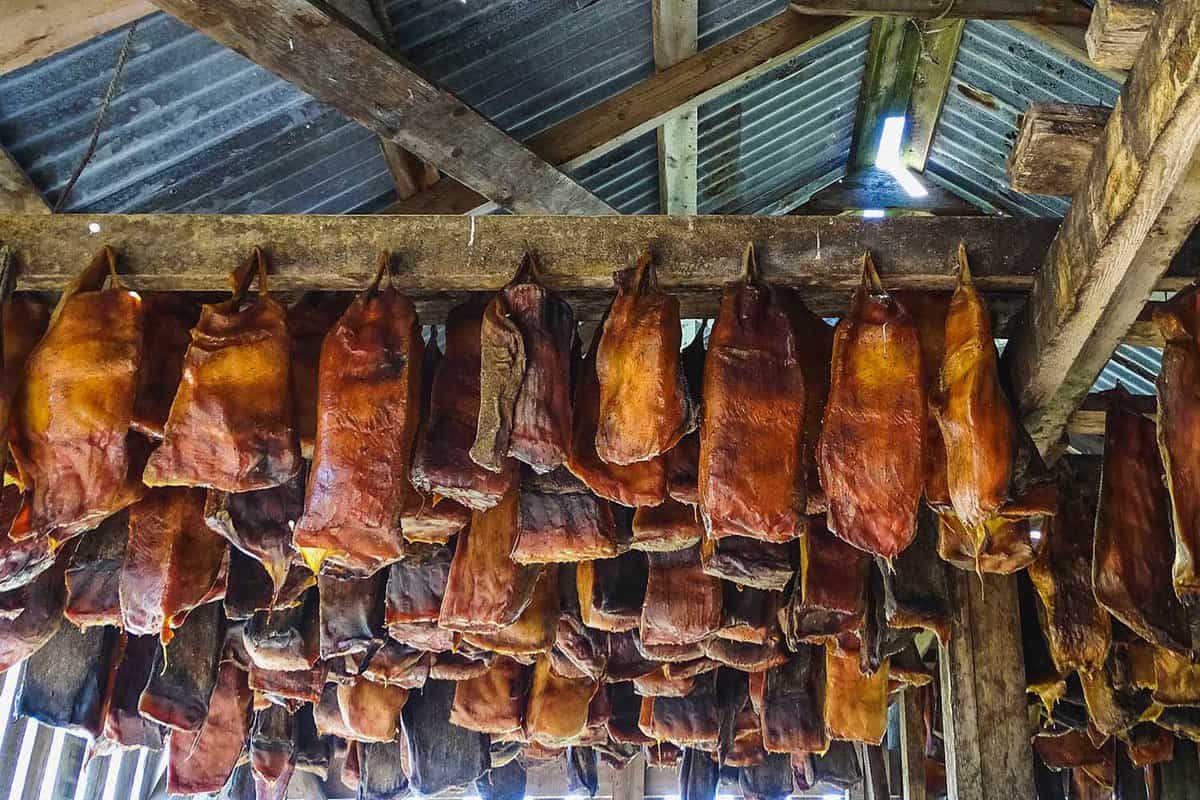 strips of brown shark hanging from ceiling of a timber hut
