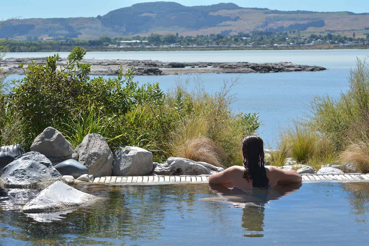 Woman staring out to a landscape from a hot spring thermal pool