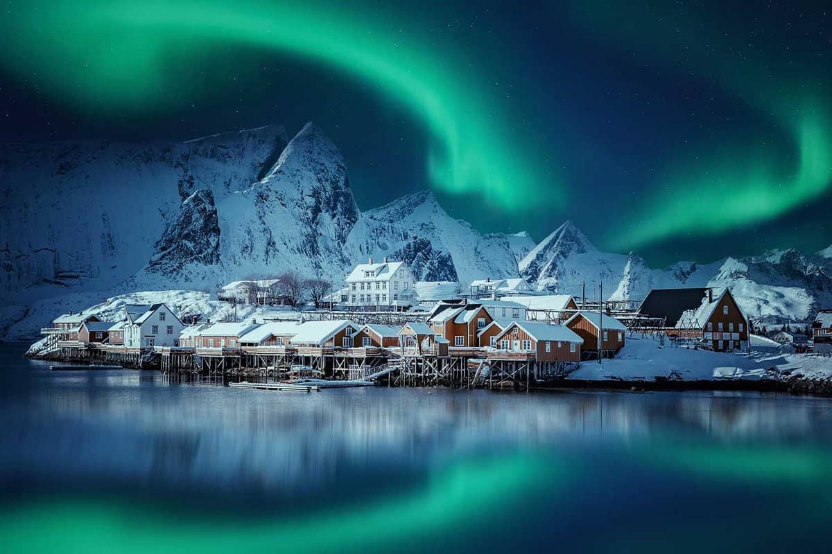 Winter scenery with aurora over Reine. Incredible winter view on snowcapped mountains, fishing village and Northern lights. Typical nature landscape of Lofoten islands. Norway. creative poscard