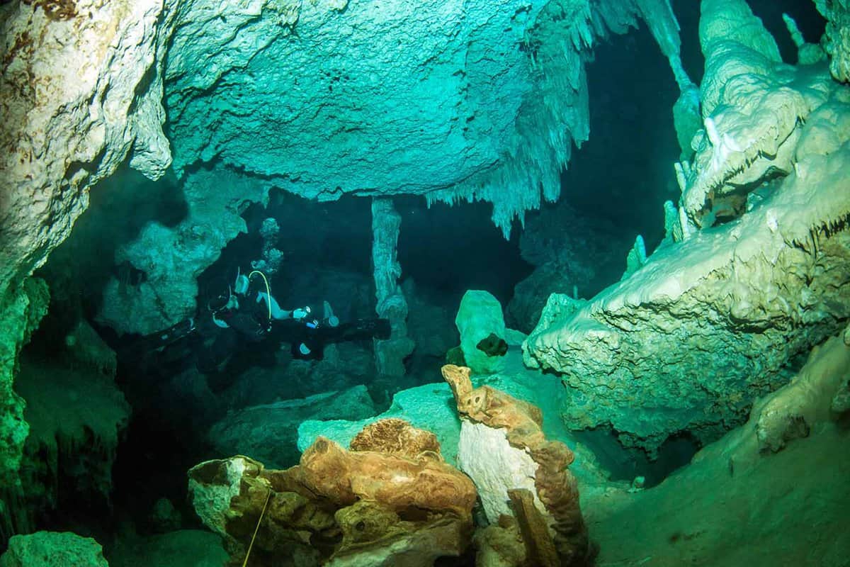 Divers swimming through the underwater caverns of Cenote Dos Ojos