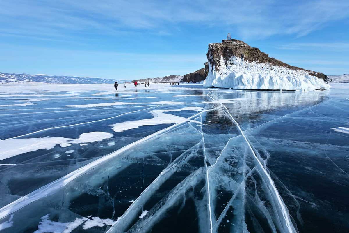 Lake Baikal frozen in winter. A group of tourists came on an excursion to the beautiful iced cape of Horin-Irgi or Cape Kobyliya Golova